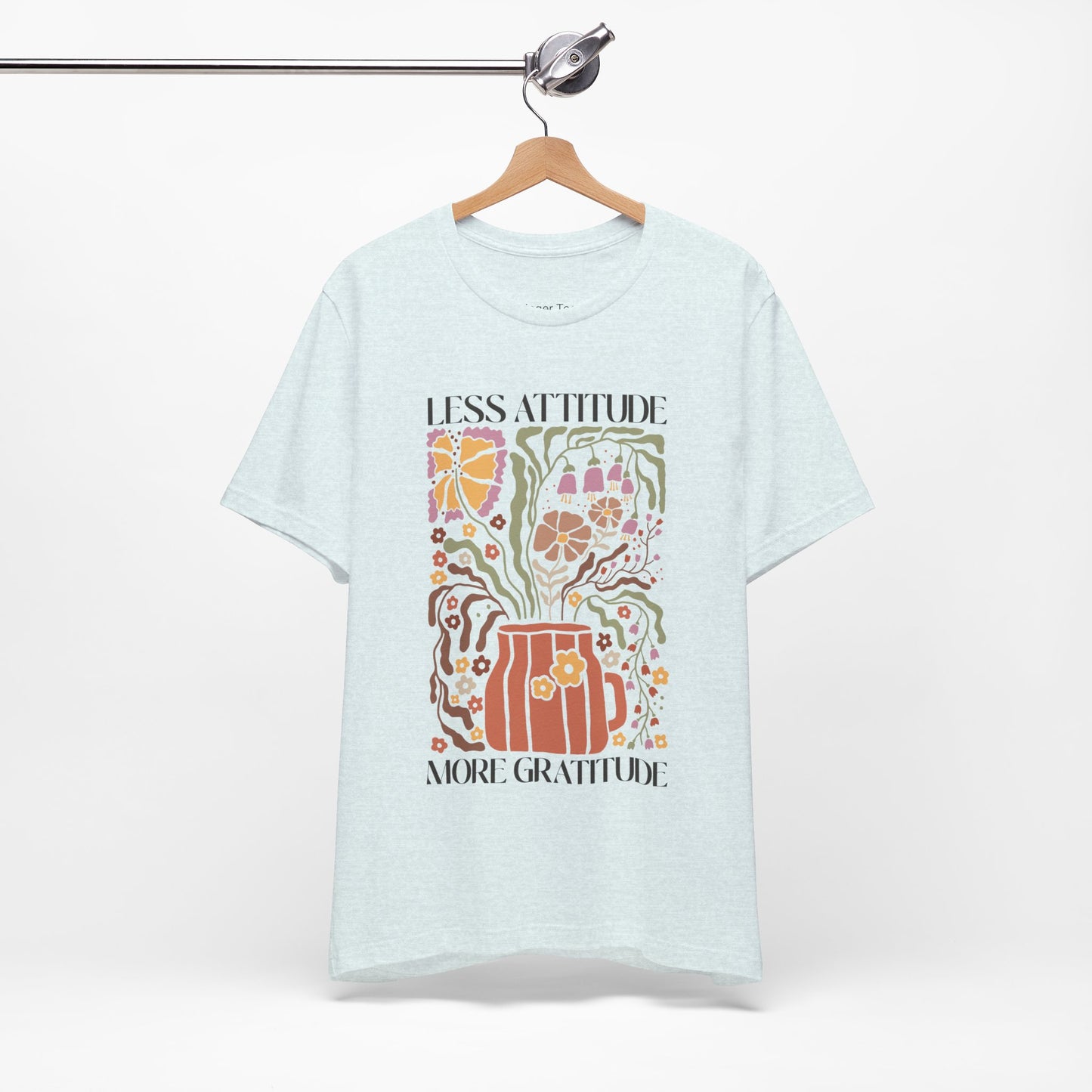 Boho-inspired t-shirt featuring the phrase 'Less Attitude More Gratitude' with vibrant floral accents and autumn colors, perfect for fall fashion and promoting positive vibes.