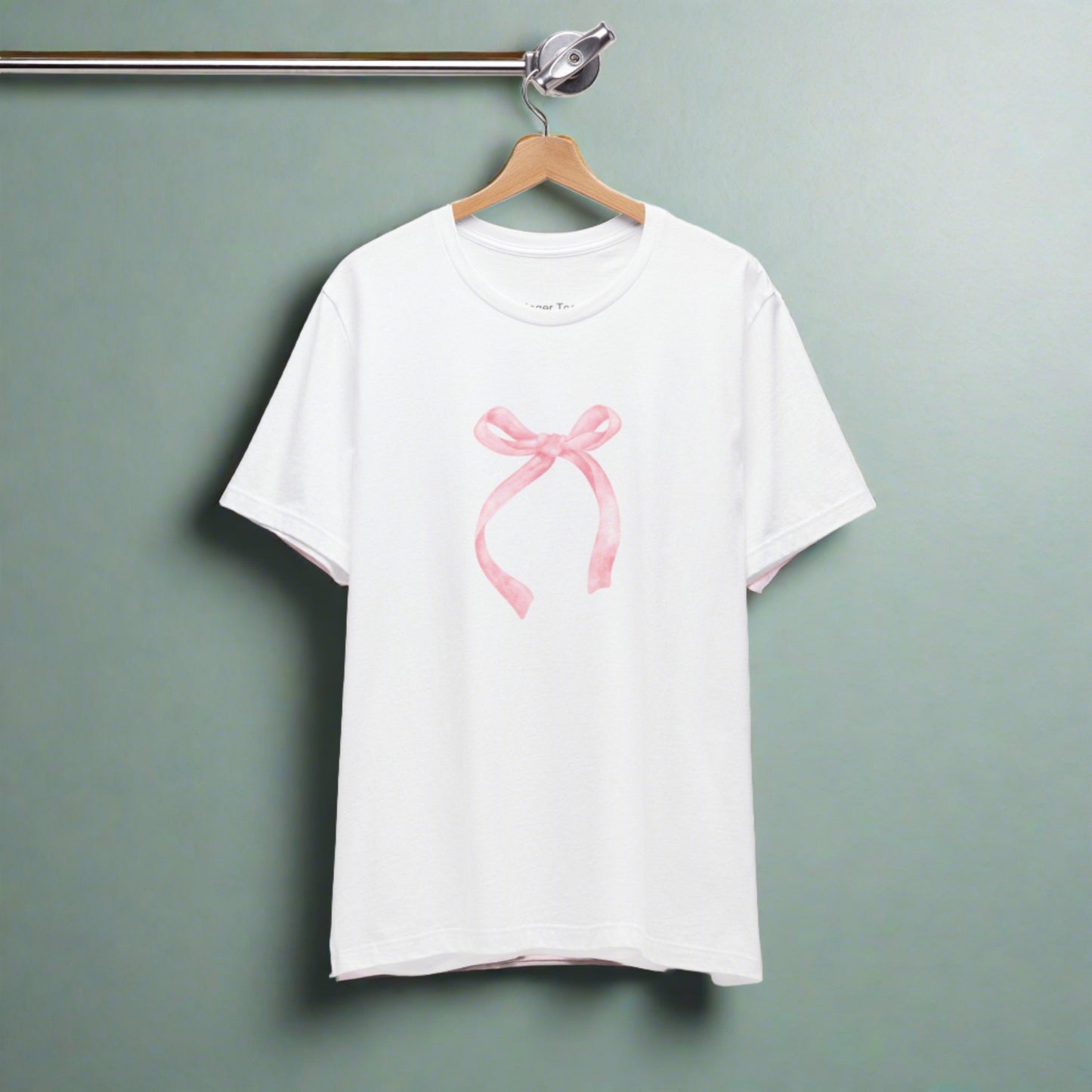 Chic coquette-style t-shirt adorned with a delicate pale pink bow at the center.