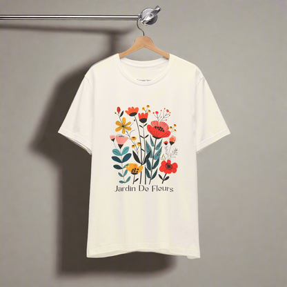 Natural t-shirt with a colorful floral design and the text 'Jardin De Fleurs' at the bottom. The design features various flowers in red, orange, yellow, and pink hues with green leaves, creating a vibrant garden look.