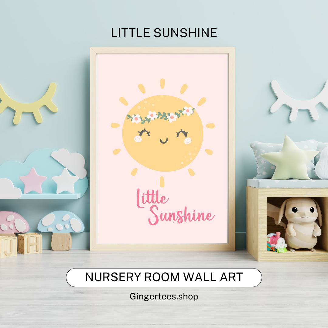 Framed nursery wall art print featuring a cheerful yellow sun with closed eyes, rosy cheeks, and a floral crown, smiling above the words “Little Sunshine” in pink script on a soft pastel pink background. Displayed in a cozy nursery room with pastel decor and plush toys.